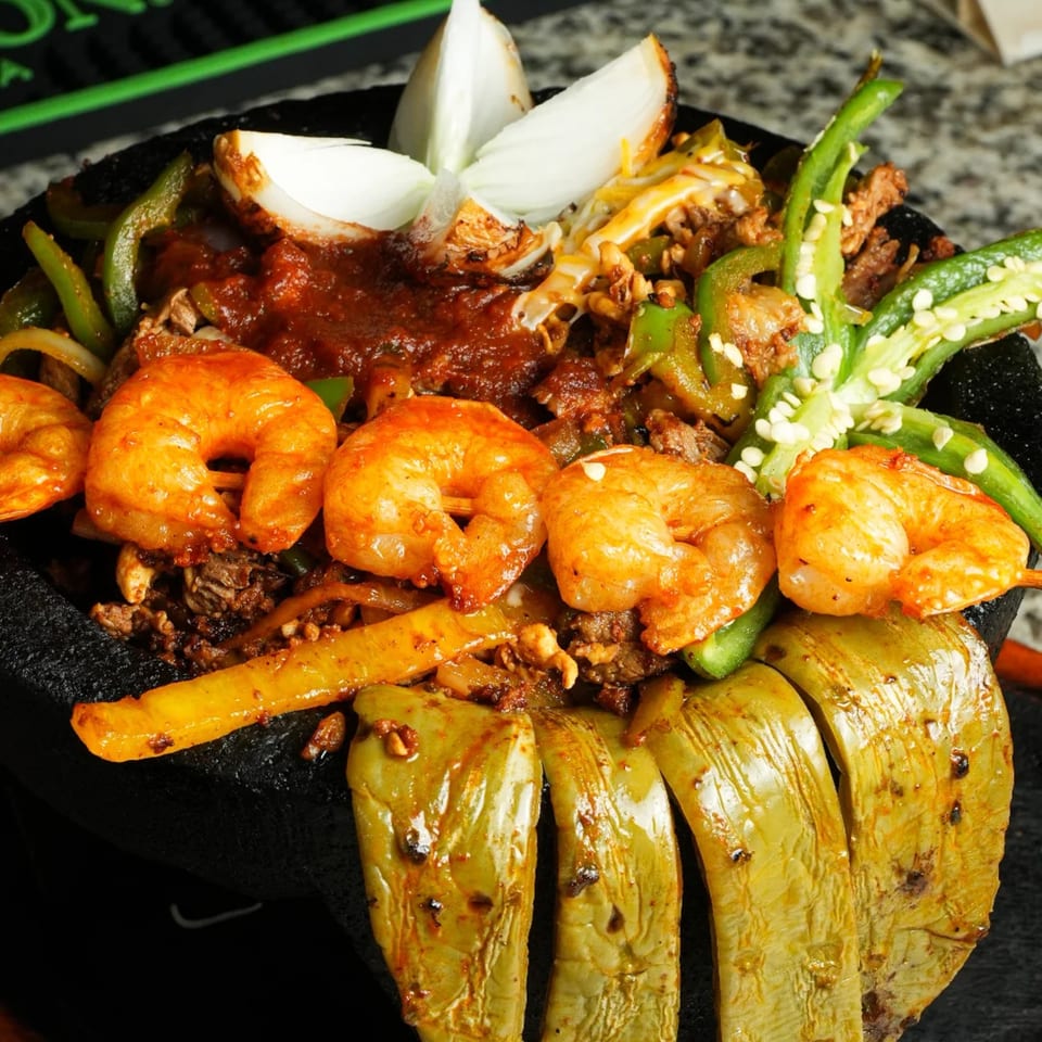 A molcajete filled with shrimp, steak, green peppers, onions, and red sauce at Los Magueyes.