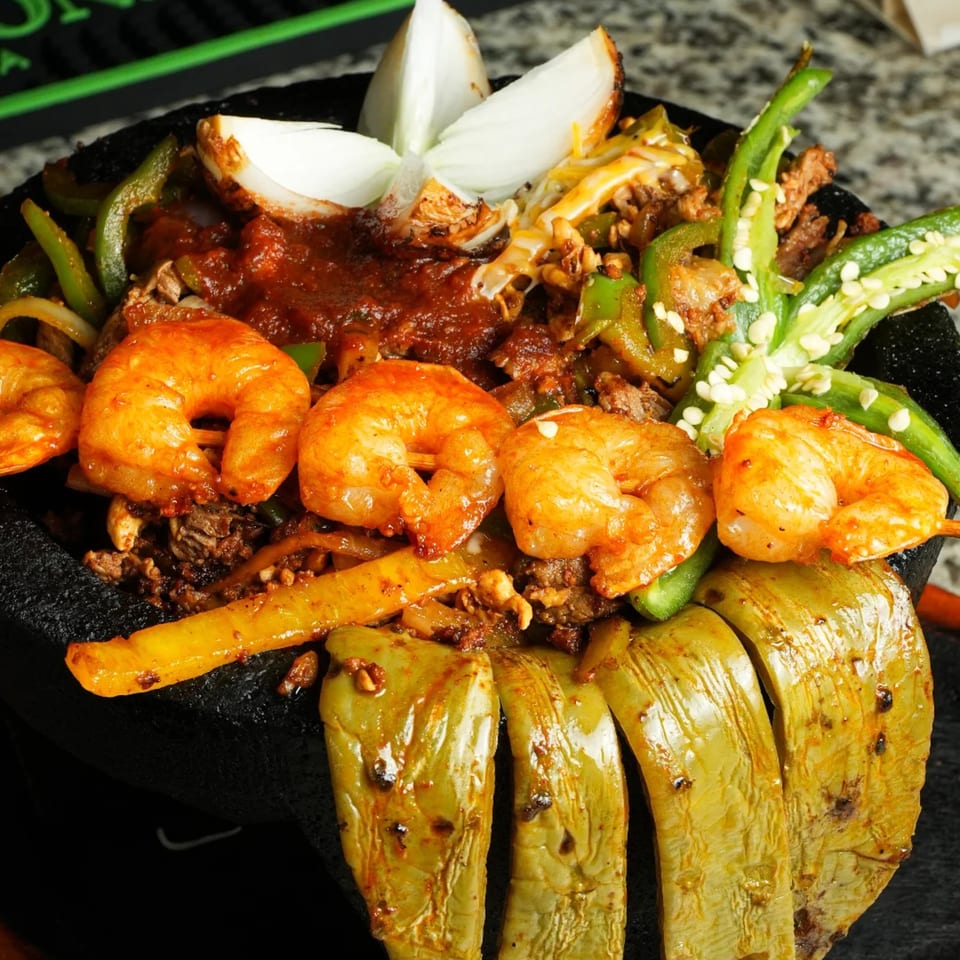 Molcajete with shrimp, steak, green peppers, onions, and red sauce at Los Magueyes.