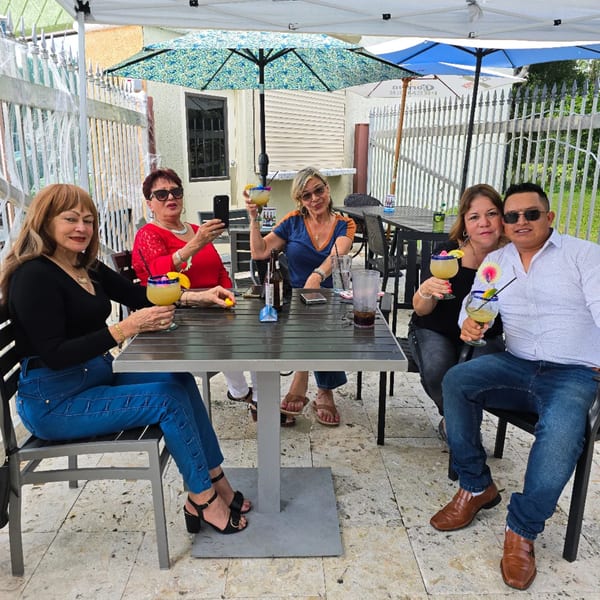 Five people enjoying margaritas and drinks at an outdoor patio table at Los Magueyes Mexican Restaurant.
